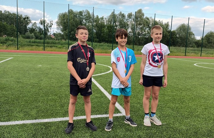 Lekka atletyka trzej zawodnicy udekorowani medalami.