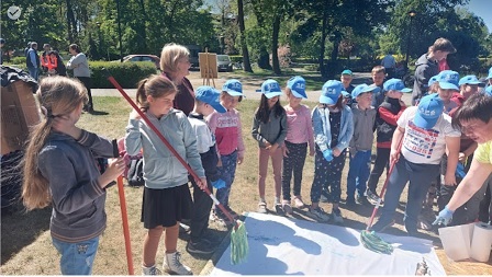 Zdjęcie przedstawia warsztaty plastyczne w parku dla uczniów klasy pierwszej i przedszkolaków 