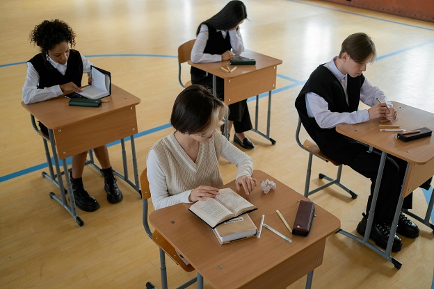 uczniowie przy stolikach na sali wykładowej
