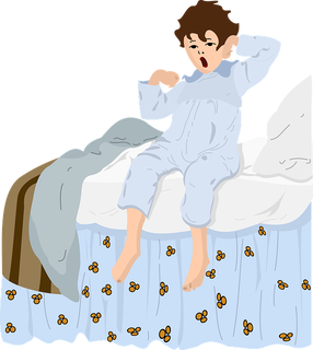 ziewający chłopiec w piżamie siedzący na łóżku