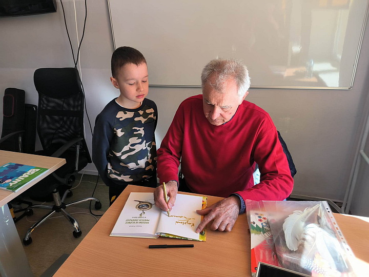Tomasz Szwed podpisujący książkę dziecku